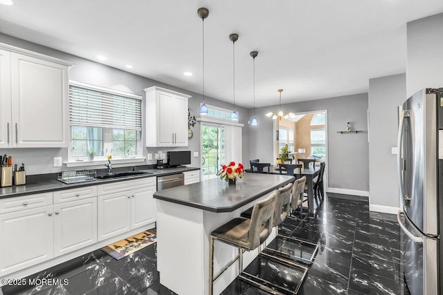 kitchen with plenty of natural light, white cabinetry, dark countertops, stainless steel appliances, and a sink