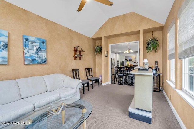 carpeted living room featuring baseboards, a ceiling fan, and vaulted ceiling