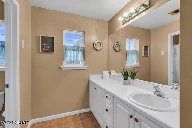 bathroom with visible vents, baseboards, vanity, and a healthy amount of sunlight