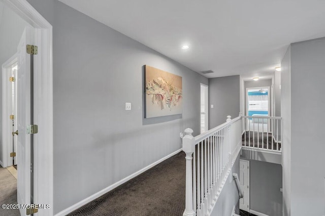 hallway featuring visible vents, baseboards, an upstairs landing, and carpet floors