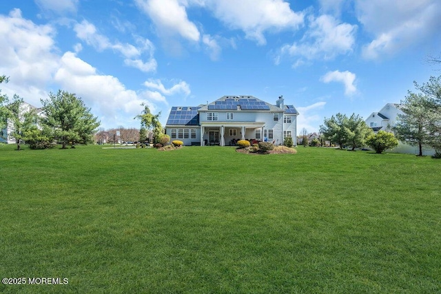 back of property featuring a yard and solar panels
