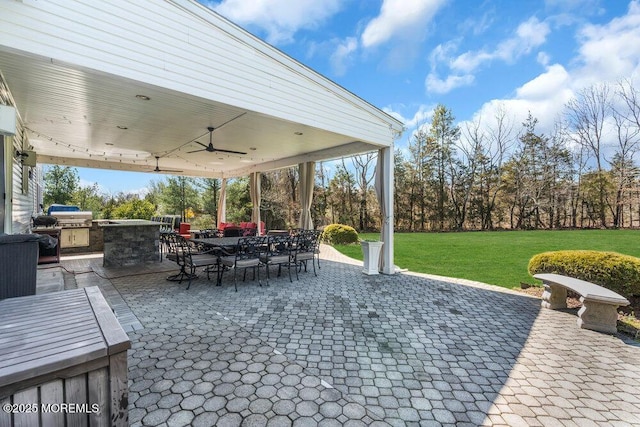 view of patio / terrace with area for grilling, an outdoor kitchen, a ceiling fan, and outdoor dining space