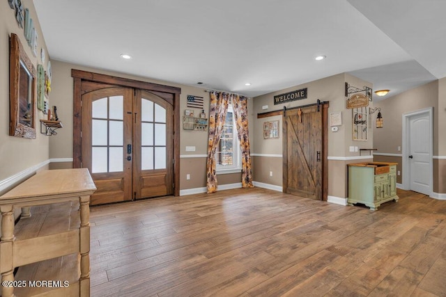 interior space featuring a barn door, french doors, baseboards, and hardwood / wood-style floors