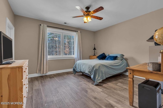 bedroom featuring visible vents, baseboards, a ceiling fan, and wood finished floors