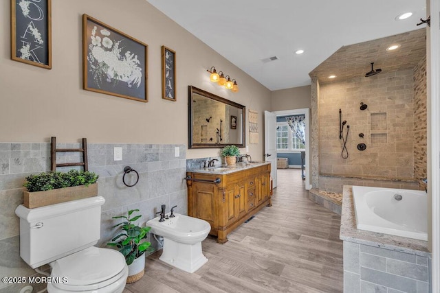 full bathroom with tile walls, visible vents, a sink, and a tile shower