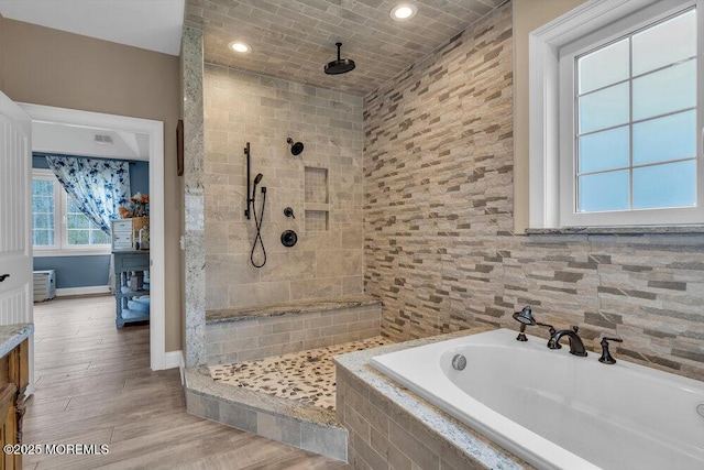 full bath with visible vents, a bath, baseboards, wood finished floors, and tiled shower