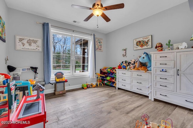 recreation room featuring light wood-style floors, baseboards, a ceiling fan, and visible vents