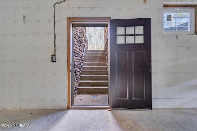 foyer featuring stairway, concrete flooring, and a healthy amount of sunlight