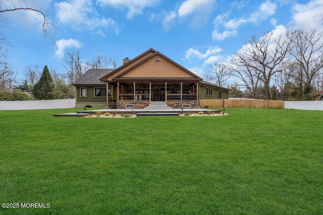 back of house with a yard, a fenced backyard, stone siding, and a chimney