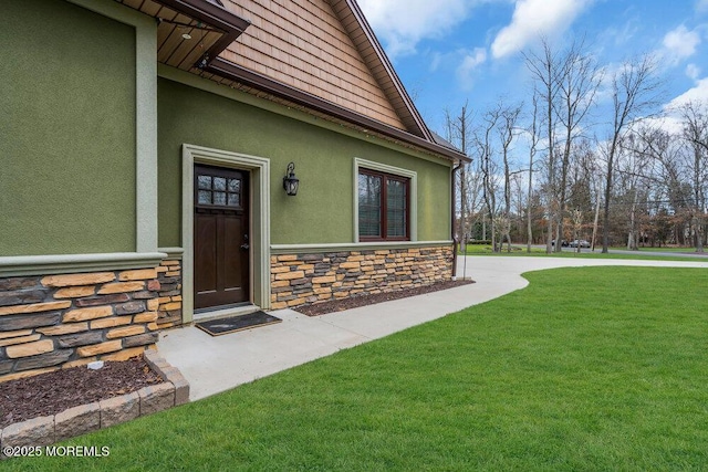doorway to property with stucco siding, stone siding, and a lawn