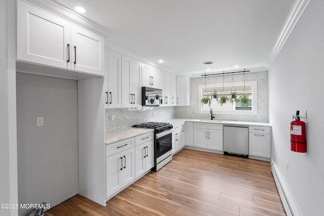 kitchen featuring ornamental molding, range with gas cooktop, dishwasher, a baseboard radiator, and a sink