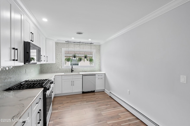 kitchen featuring a sink, ornamental molding, appliances with stainless steel finishes, recessed lighting, and a baseboard heating unit