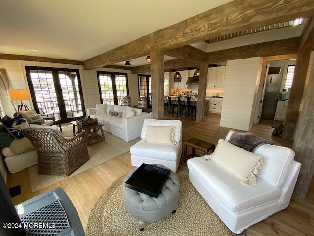 living room with wooden walls, beamed ceiling, and wood finished floors