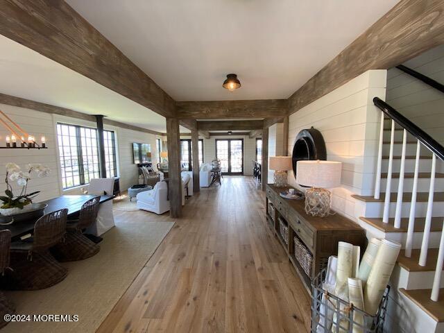 hall with stairway, a notable chandelier, beam ceiling, and hardwood / wood-style flooring