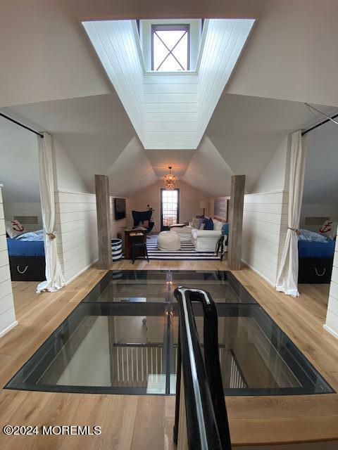 bedroom featuring wood finished floors and lofted ceiling with skylight