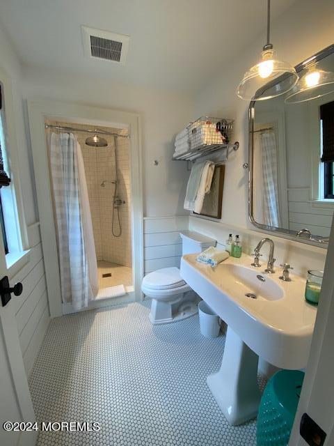 full bathroom with a shower stall, toilet, visible vents, and a wainscoted wall