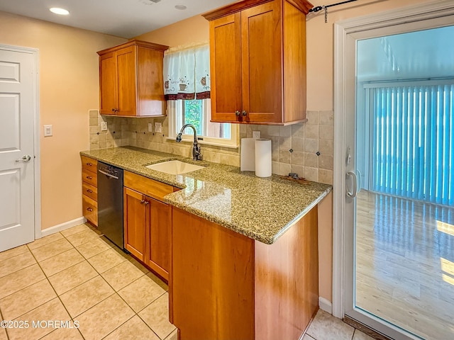 kitchen featuring tasteful backsplash, light tile patterned floors, black dishwasher, a sink, and brown cabinets