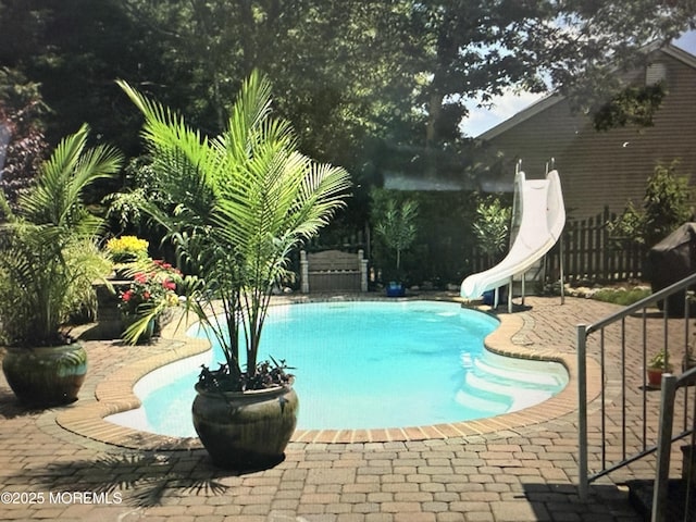 outdoor pool featuring a patio area, fence, and a water slide