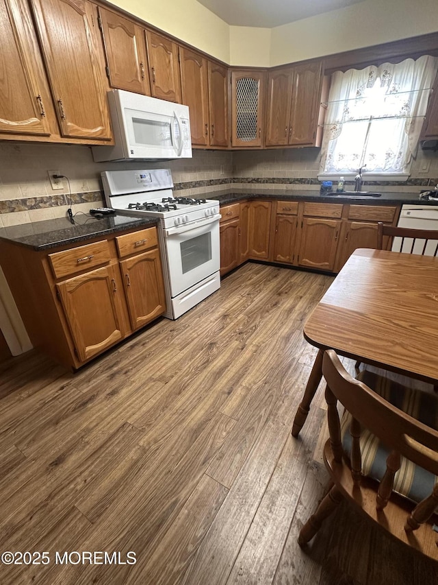kitchen featuring dark countertops, white appliances, decorative backsplash, and dark wood finished floors