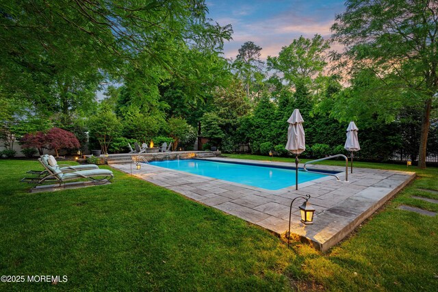 491 Clinton Ave, Toms River, NJ 08753 - pool at dusk with a patio area, a lawn, and view of wooded area