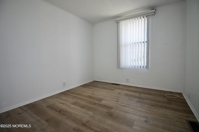 empty room with visible vents, baseboards, and wood finished floors