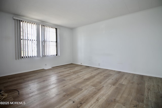 spare room with baseboards and wood finished floors