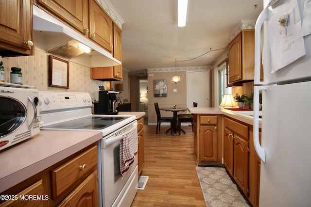 kitchen with under cabinet range hood, white appliances, light wood-style floors, and light countertops