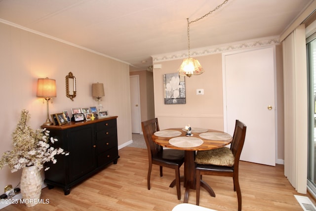 dining space with ornamental molding, visible vents, and light wood-style flooring