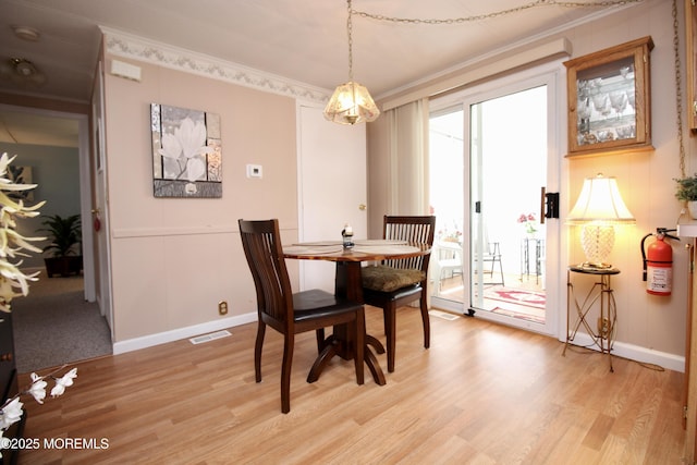 dining area featuring light wood-style flooring, baseboards, ornamental molding, and visible vents