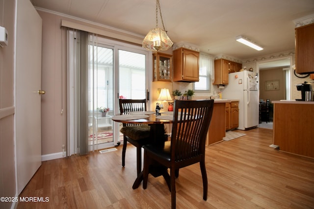 dining room featuring light wood-style flooring, baseboards, ornamental molding, and visible vents