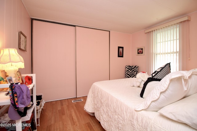 bedroom featuring wood finished floors, a closet, and visible vents