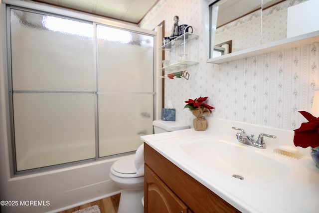 bathroom featuring shower / bath combination with glass door, vanity, wallpapered walls, toilet, and wood finished floors