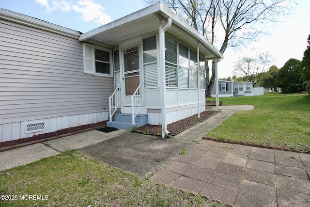 view of exterior entry featuring crawl space and a yard