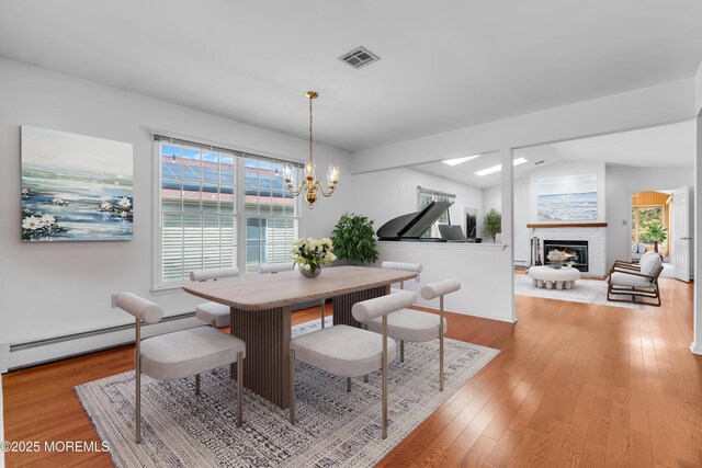 1905 Cherryvale Ct, Toms River, NJ 08755 - dining area with baseboard heating, a chandelier, light wood finished floors, a fireplace, and vaulted ceiling
