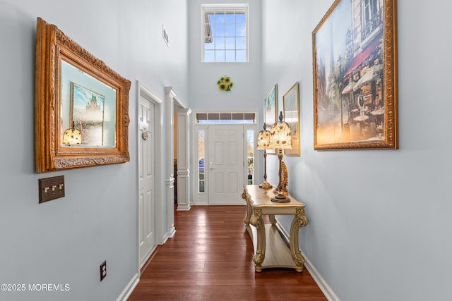 entrance foyer with baseboards, ornate columns, a high ceiling, and dark wood finished floors