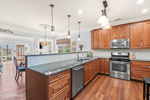 kitchen featuring a peninsula, visible vents, appliances with stainless steel finishes, a sink, and decorative backsplash