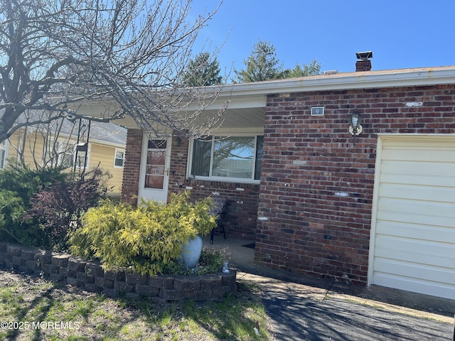 entrance to property with a chimney and brick siding