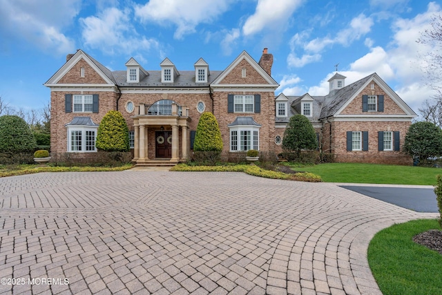 colonial house with a chimney, a front lawn, and brick siding