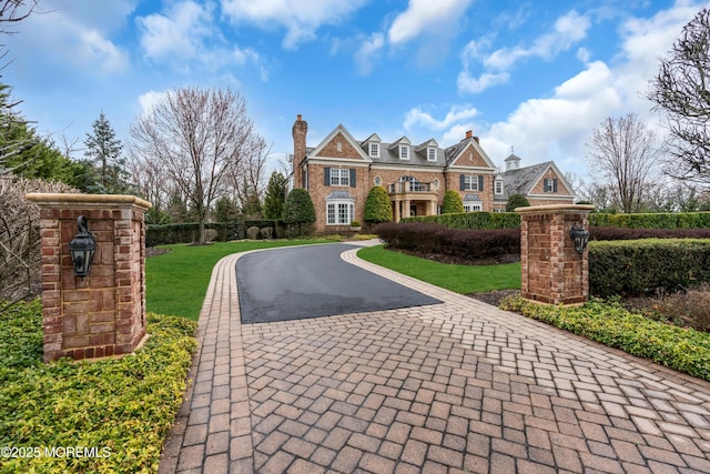 view of front of property featuring a chimney, aphalt driveway, and a front yard