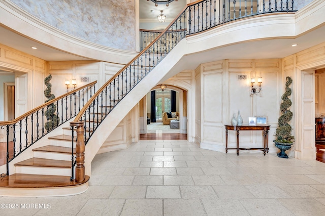 entryway with arched walkways, a decorative wall, a high ceiling, and stairs