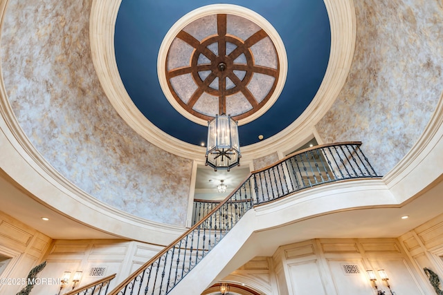 staircase with a chandelier, ornamental molding, and a high ceiling