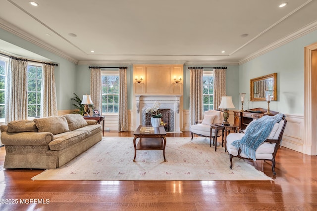 living room featuring wood finished floors, a high end fireplace, wainscoting, and plenty of natural light