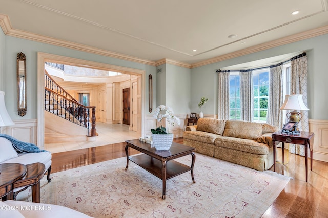 living area with ornamental molding, wainscoting, and stairs