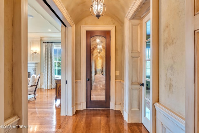 entrance foyer featuring wood finished floors, ornamental molding, and lofted ceiling