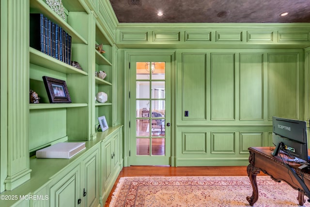 home office featuring recessed lighting, a decorative wall, built in shelves, and light wood-style flooring
