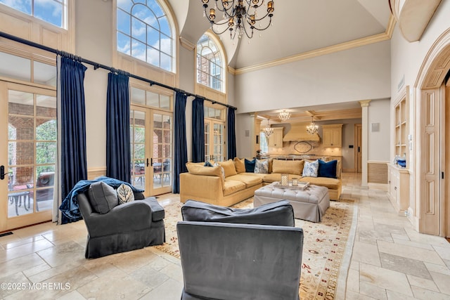 living area with a chandelier, a wealth of natural light, french doors, and stone tile floors