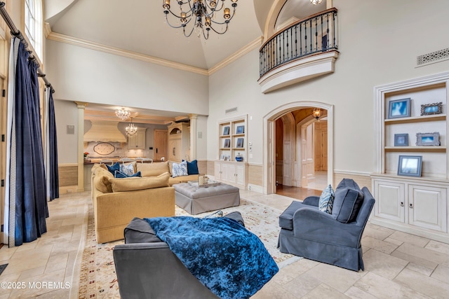 living area with a chandelier, arched walkways, a towering ceiling, and ornamental molding