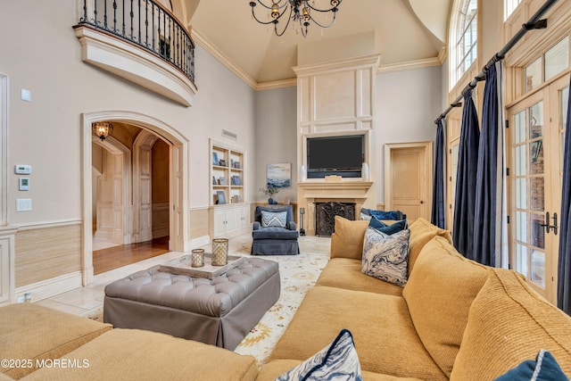 living room featuring visible vents, built in features, arched walkways, a notable chandelier, and a towering ceiling