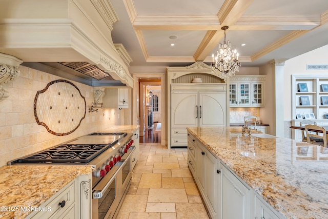 kitchen with custom exhaust hood, coffered ceiling, high quality appliances, a notable chandelier, and stone tile flooring