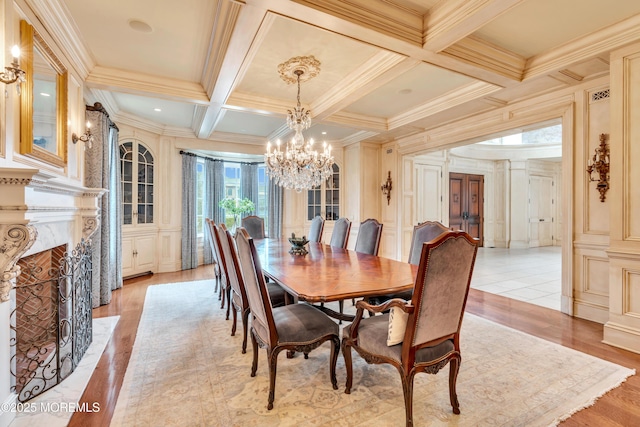 dining room featuring a notable chandelier, a high end fireplace, crown molding, beam ceiling, and coffered ceiling